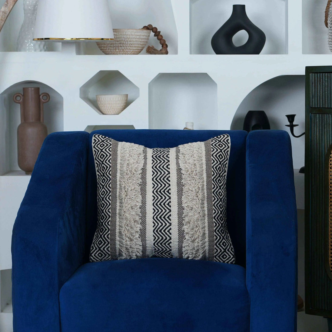 Boho textured pillow on deep blue velvet armchair.