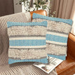 Set of two boho throw pillow covers with blue chevron patterns, beige shaggy textured stripes, and neutral gray bands, styled on a leather couch in a cozy modern living room.
