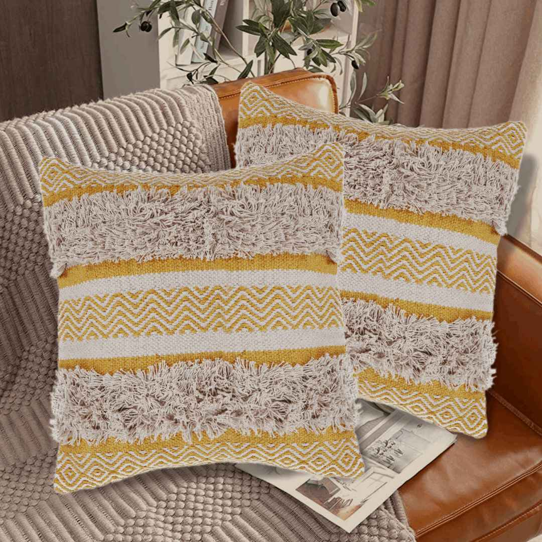 Set of two yellow and beige tufted decorative pillows with zigzag and shaggy textured stripes, styled on a tan leather couch with a cozy knit throw and natural light ambiance.