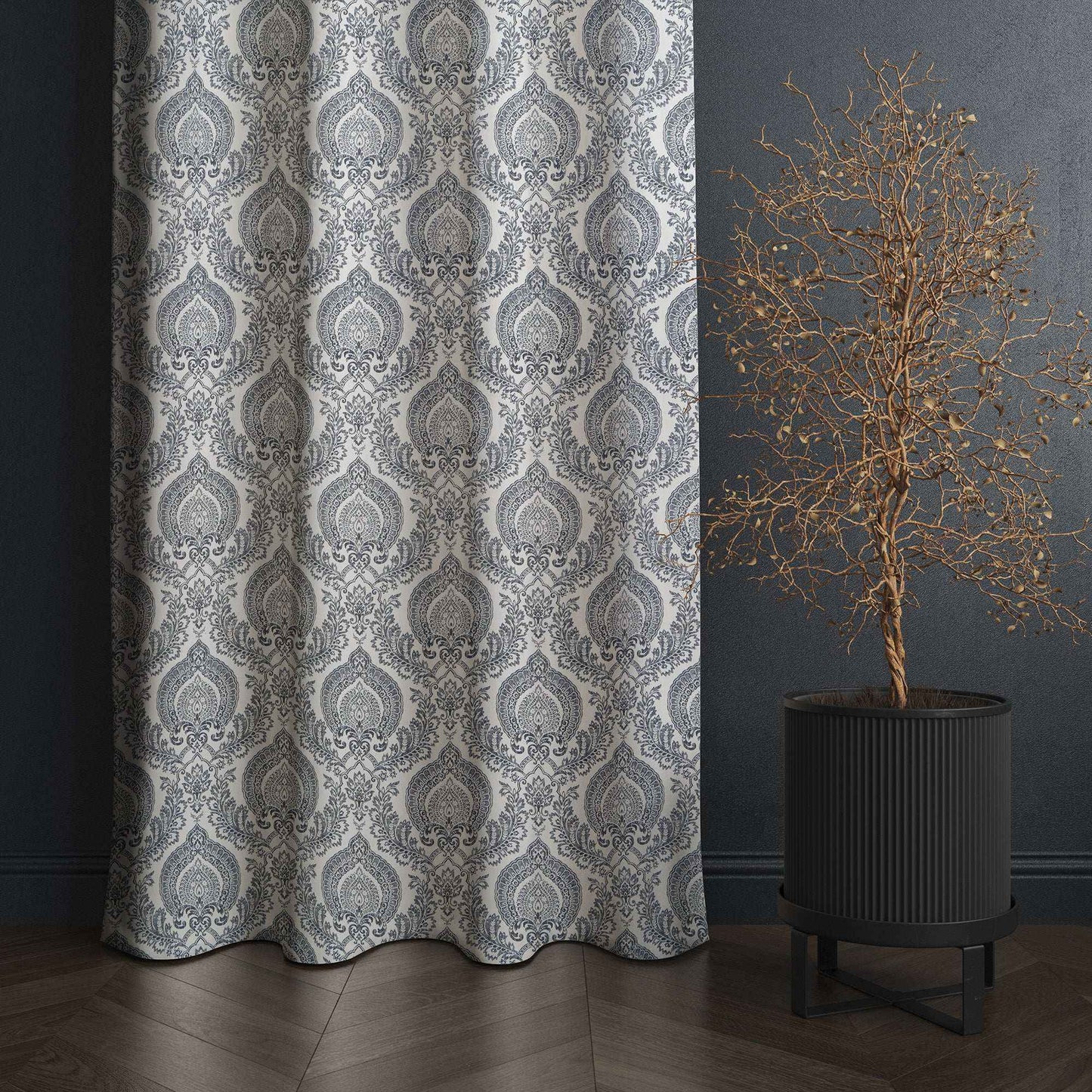 Gray and white damask patterned curtain styled in a dark modern interior with wood flooring, featuring a decorative dried tree in a black planter for a chic home accent.