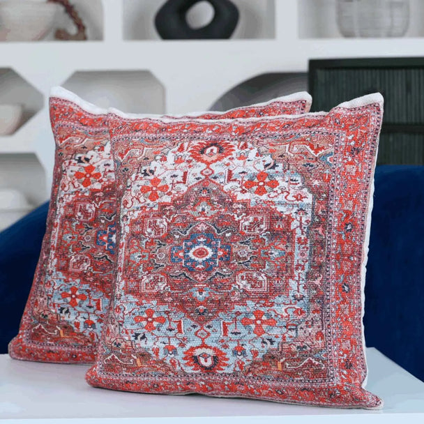 "Pair of decorative throw pillows with intricate red, blue, and white Persian-style medallion pattern placed on a modern white surface with a navy blue sofa and shelf backdrop."