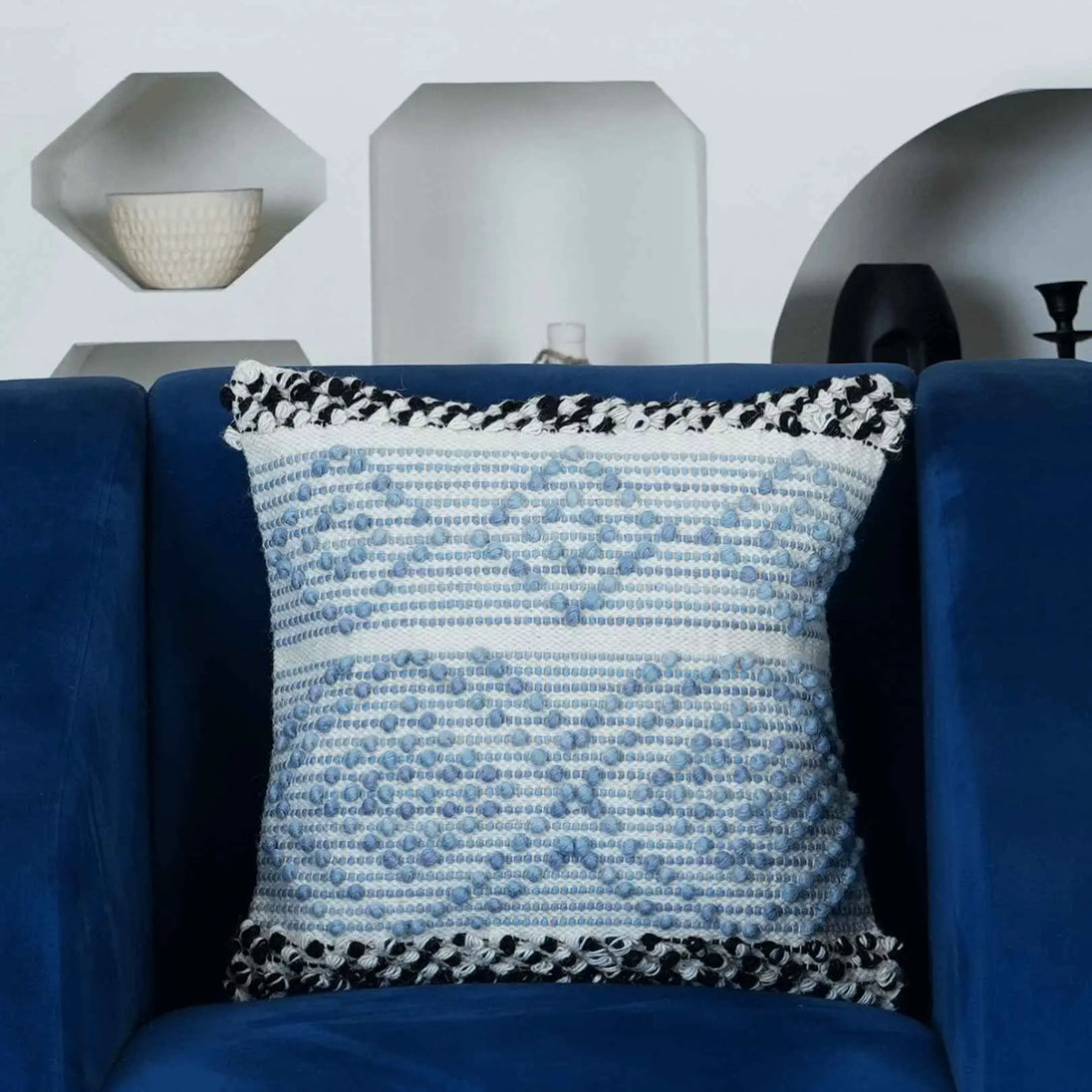 Blue textured pillow with black trim on navy sofa.
