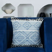 Blue textured pillow with black trim on navy sofa.
