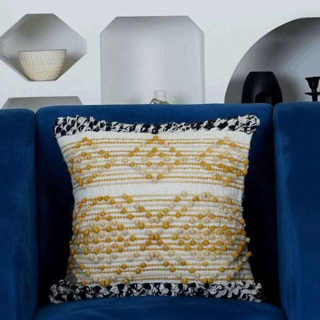 Yellow and white boho cushion on navy chair.

