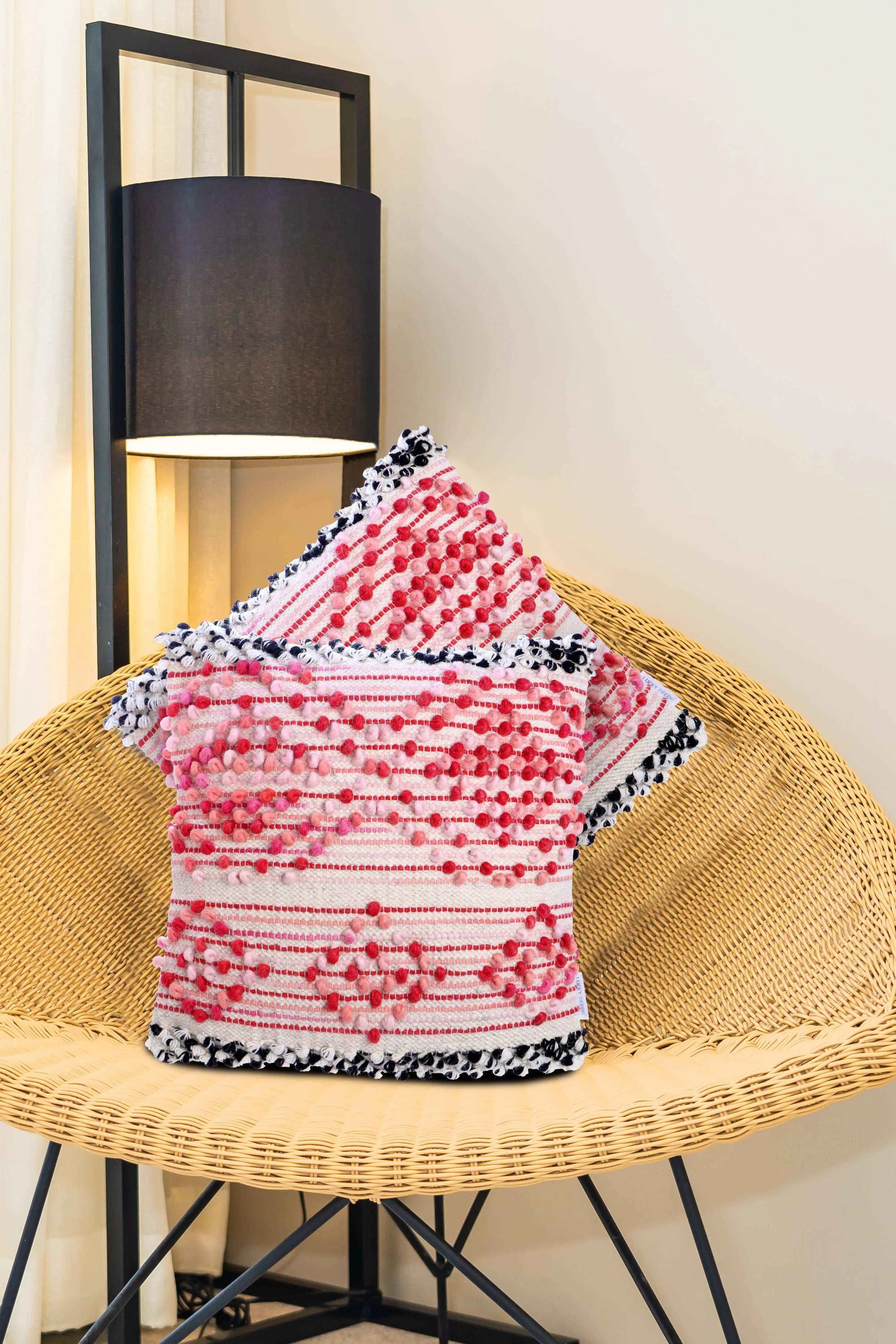 Textured red boho throw pillows on wicker chair.
