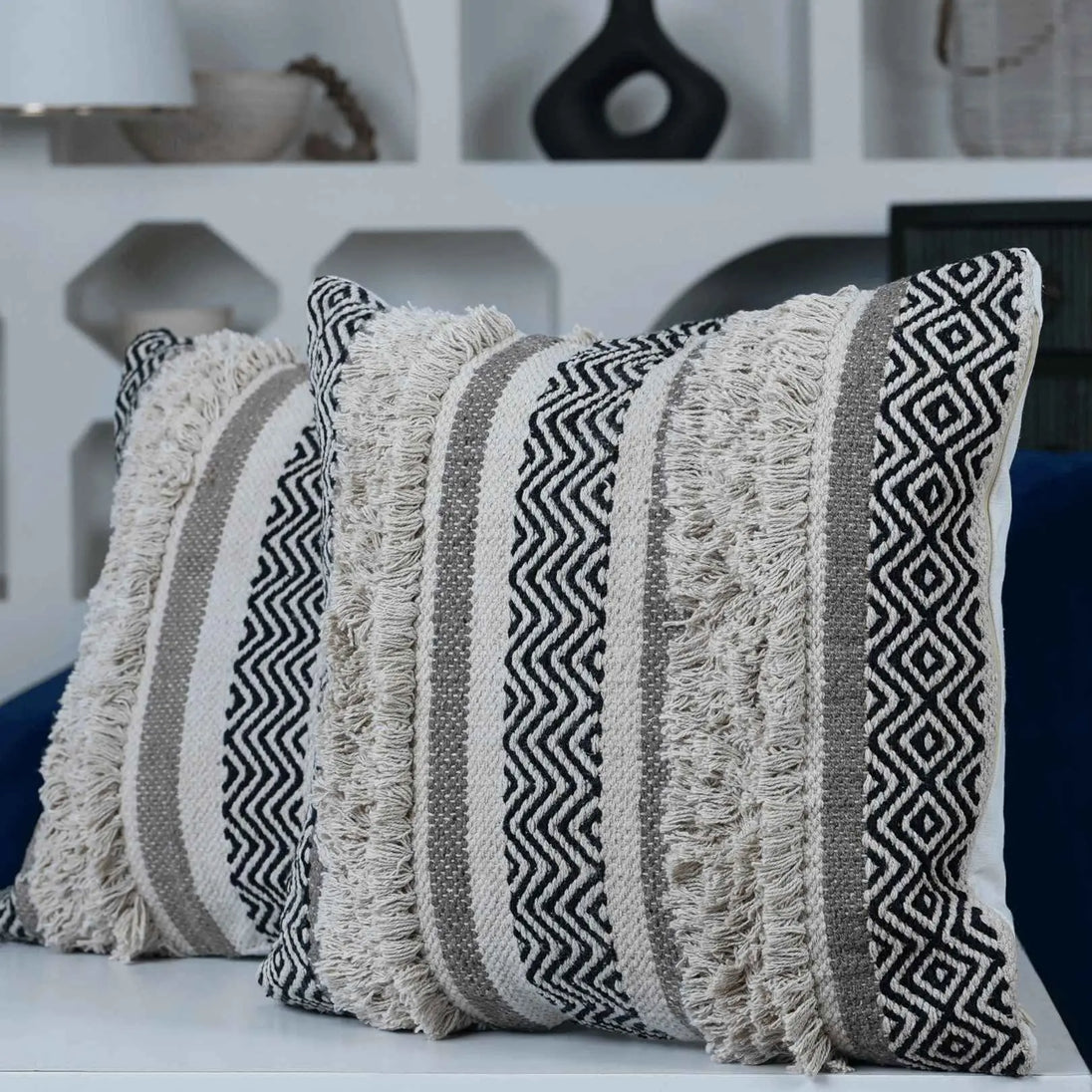Set of two boho fringe pillows with geometric patterns.