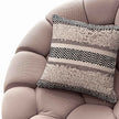 Boho accent pillow on modern textured lounge chair.
