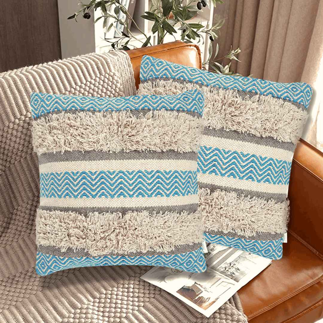 Set of two boho throw pillow covers with blue chevron patterns, beige shaggy textured stripes, and neutral gray bands, styled on a leather couch in a cozy modern living room.







