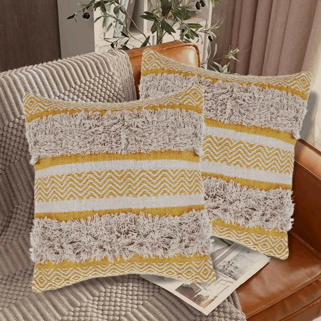 Pair of yellow boho pillows on leather sofa.
