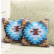 Pair of tribal print throw pillows with bold zigzag patterns in turquoise blue, mustard yellow, and maroon, placed on a textured beige sofa for a modern Southwestern home decor look.