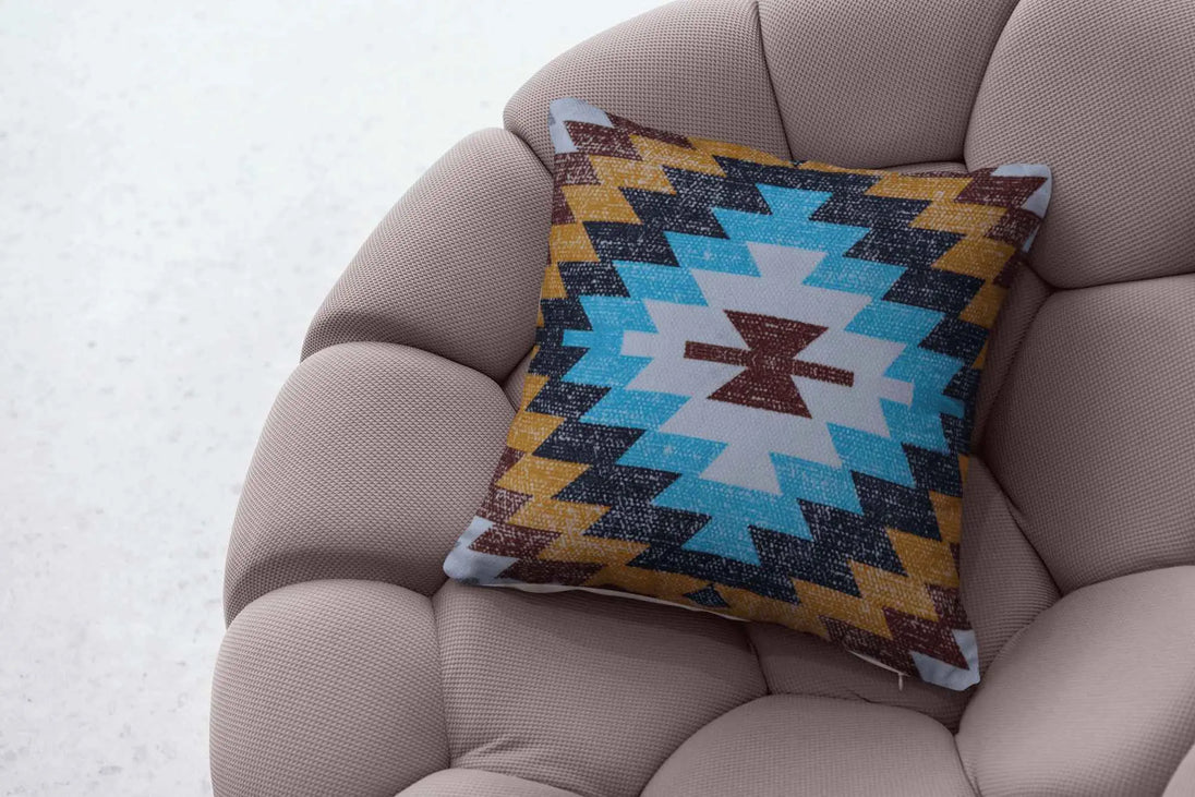 Southwestern tribal print throw pillow with bold geometric patterns in turquoise, mustard yellow, maroon, and black, placed on a modern tufted beige armchair, creating a cozy and stylish accent.