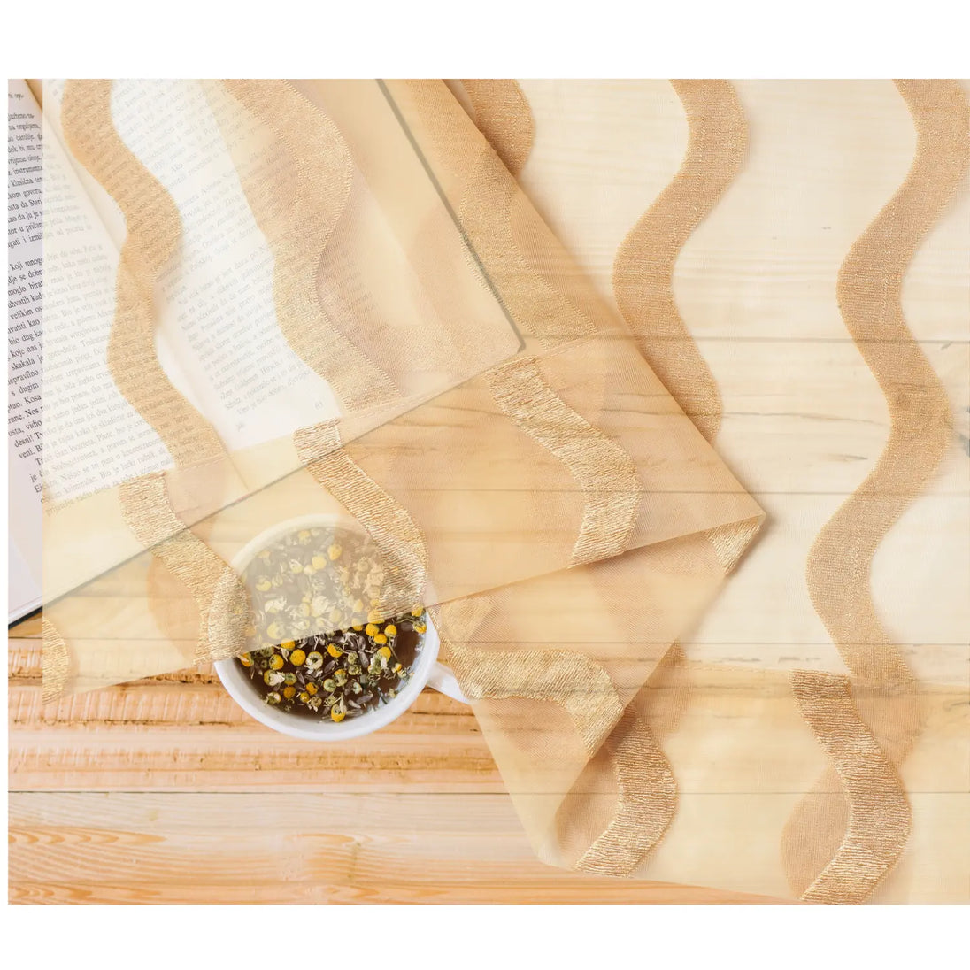 Gold wave sheer fabric over tea and book.
