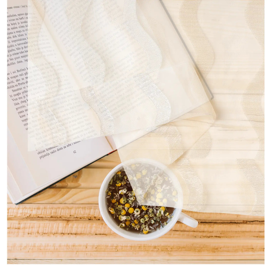 Tea bag in a cup of tea on an open book with a wooden surface