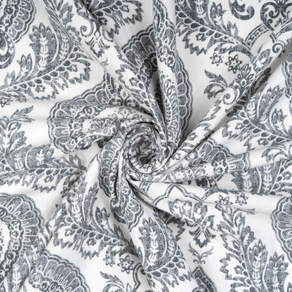 Twisted swirl of gray damask patterned cotton fabric highlighting texture, softness, and intricate floral detailing for curtain or upholstery use.







