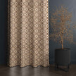 Geometric brown curtain beside modern potted plant.
