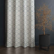 Gray geometric curtain next to modern potted plant.
