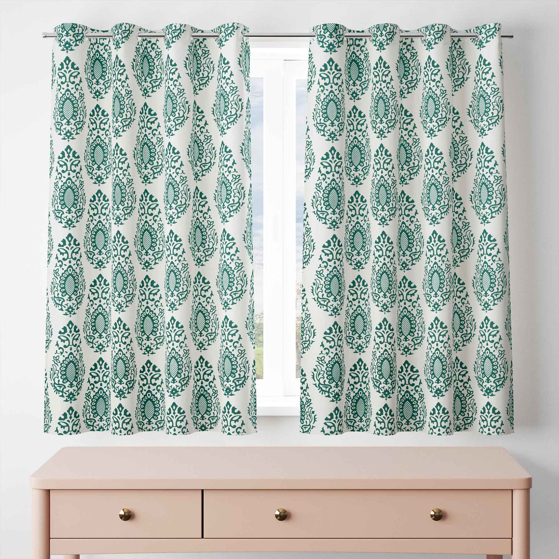 Green damask curtains hanging on window above dresser.
