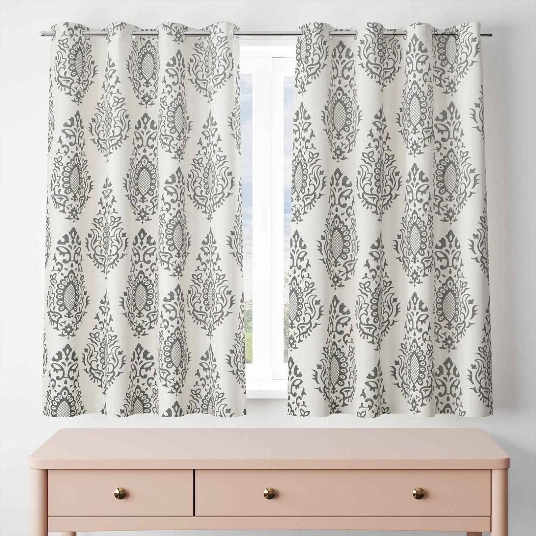 Short gray damask curtains above blush pink dresser
