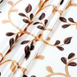 Close-up of white curtain fabric with a gold and brown leafy vine print, 